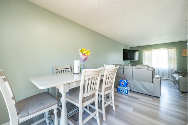 102 Wall Ave, Des Moines, IA 50315 - dining area featuring wood finished floors, a textured ceiling, and vaulted ceiling