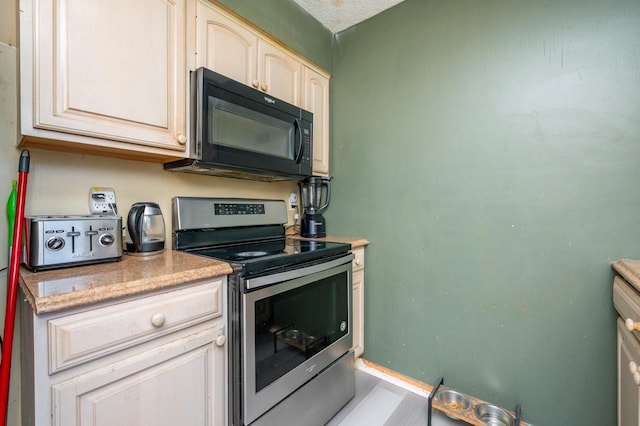 102 Wall Ave, Des Moines, IA 50315 - kitchen featuring black microwave, stainless steel range with electric cooktop, light countertops, and baseboards