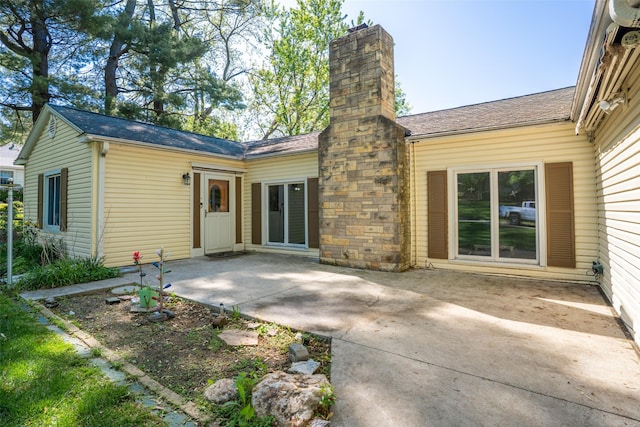 rear view of property featuring a chimney and a patio area