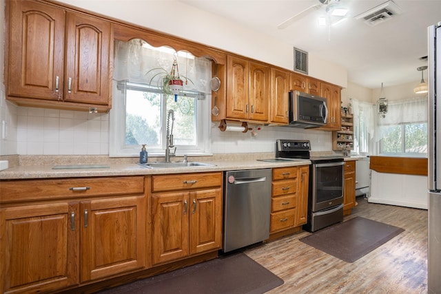 kitchen with stainless steel appliances, brown cabinets, healthy amount of natural light, and a sink