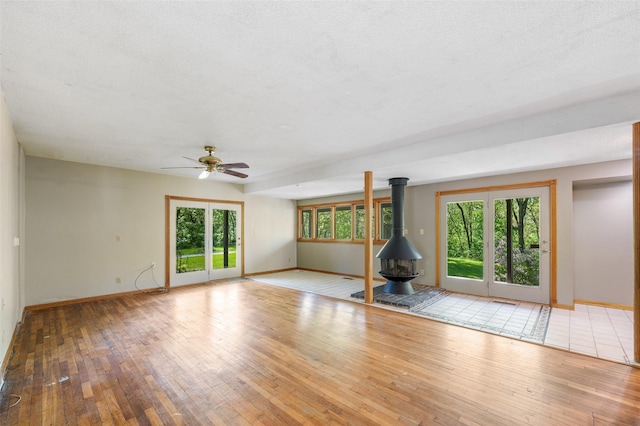 3936 Hubbell Ave, Des Moines, IA 50317 - unfurnished living room with a wood stove, a ceiling fan, baseboards, hardwood / wood-style flooring, and a textured ceiling