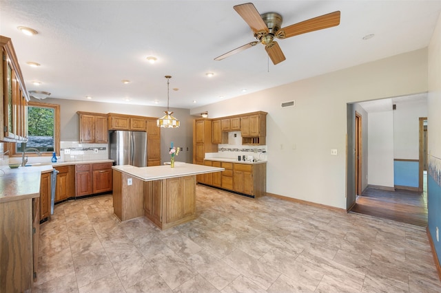 3936 Hubbell Ave, Des Moines, IA 50317 - kitchen featuring freestanding refrigerator, tasteful backsplash, light countertops, a kitchen island, and ceiling fan