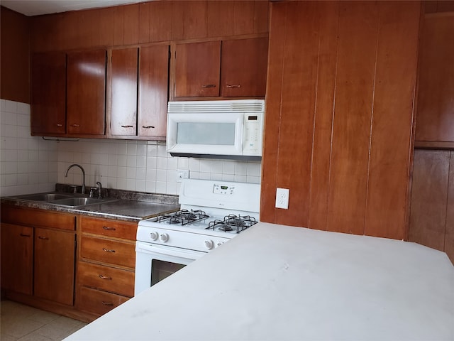 1344 21st St, Des Moines, IA 50311 - kitchen featuring white appliances, a sink, brown cabinetry, and decorative backsplash