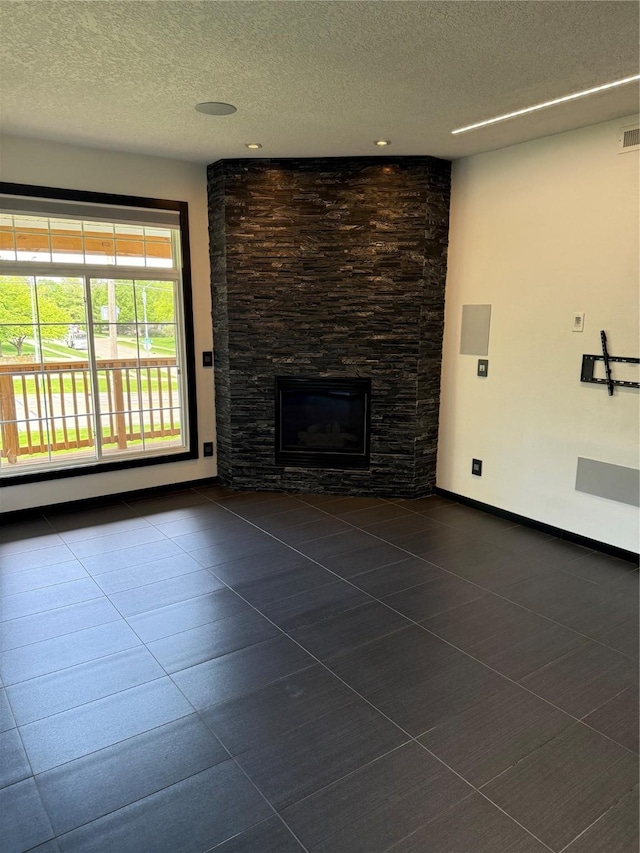 950 67th St Unit 321, West Des Moines, IA 50266 - unfurnished living room featuring a textured ceiling, dark tile patterned flooring, and a stone fireplace