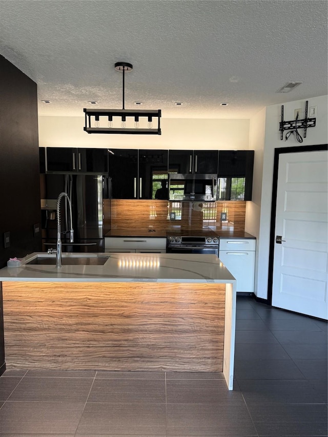 950 67th St Unit 321, West Des Moines, IA 50266 - kitchen with appliances with stainless steel finishes, a textured ceiling, dark cabinets, dark tile patterned floors, and a sink