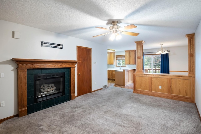 1634 Prairie Cir, Altoona, IA 50009 - unfurnished living room featuring a chandelier, ceiling fan, a tile fireplace, light carpet, and a sink