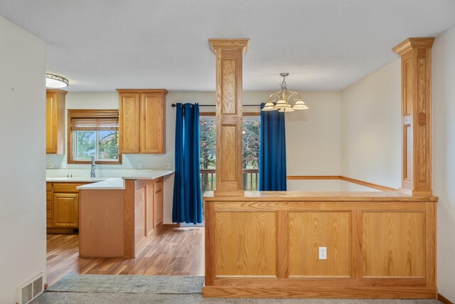 1634 Prairie Cir, Altoona, IA 50009 - kitchen with ornate columns, light wood-style floors, a sink, a chandelier, and light countertops