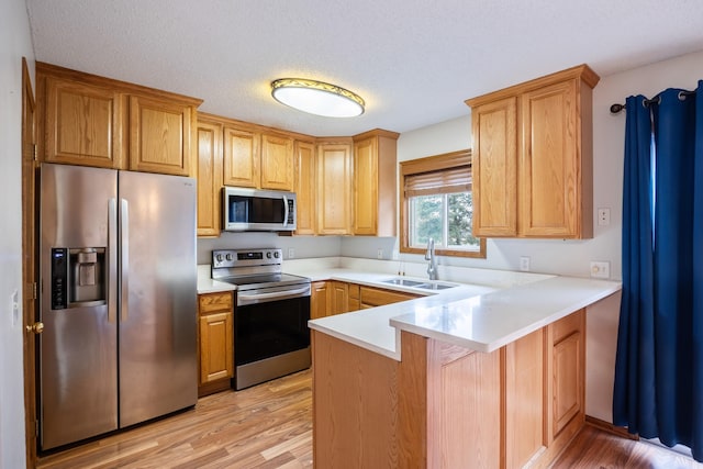 1634 Prairie Cir, Altoona, IA 50009 - kitchen with appliances with stainless steel finishes, a sink, light wood-type flooring, a peninsula, and light countertops