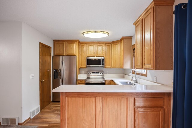 1634 Prairie Cir, Altoona, IA 50009 - kitchen featuring appliances with stainless steel finishes, a sink, light wood-style floors, light countertops, and a peninsula
