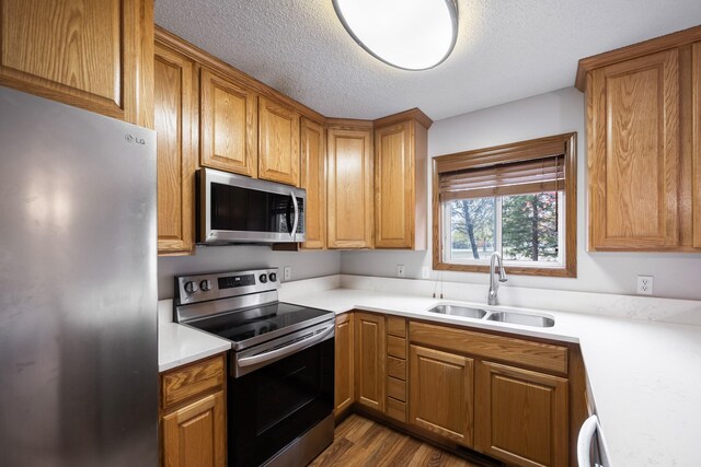 1634 Prairie Cir, Altoona, IA 50009 - kitchen with stainless steel appliances, a sink, a textured ceiling, dark wood-style flooring, and light countertops