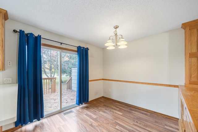 1634 Prairie Cir, Altoona, IA 50009 - unfurnished dining area with a chandelier, light wood-style flooring, and a textured ceiling