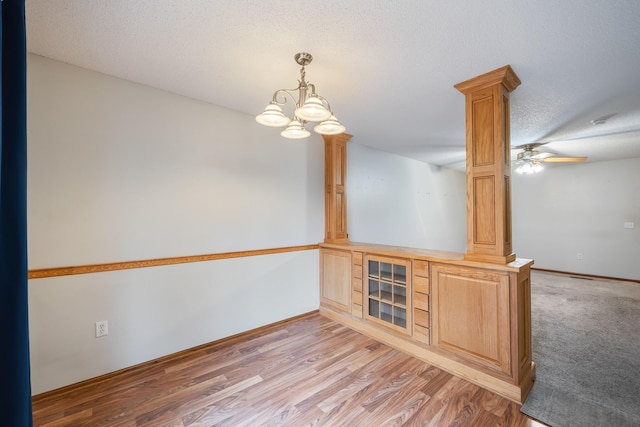 1634 Prairie Cir, Altoona, IA 50009 - unfurnished room with ornate columns, a chandelier, light wood-style floors, baseboards, and a textured ceiling