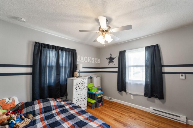 3101 Roblang Ct, Des Moines, IA 50317 - bedroom with baseboard heating, wood finished floors, a textured ceiling, baseboards, and a ceiling fan