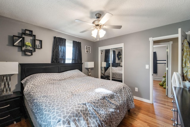 3101 Roblang Ct, Des Moines, IA 50317 - bedroom with wood finished floors, a closet, a textured ceiling, baseboards, and a baseboard heating unit