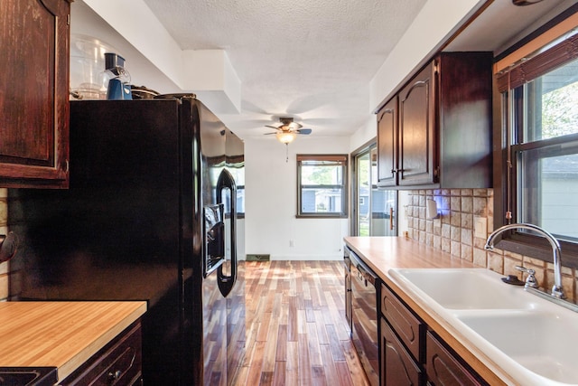 3101 Roblang Ct, Des Moines, IA 50317 - kitchen with black fridge, a sink, light wood-style flooring, tasteful backsplash, and light countertops