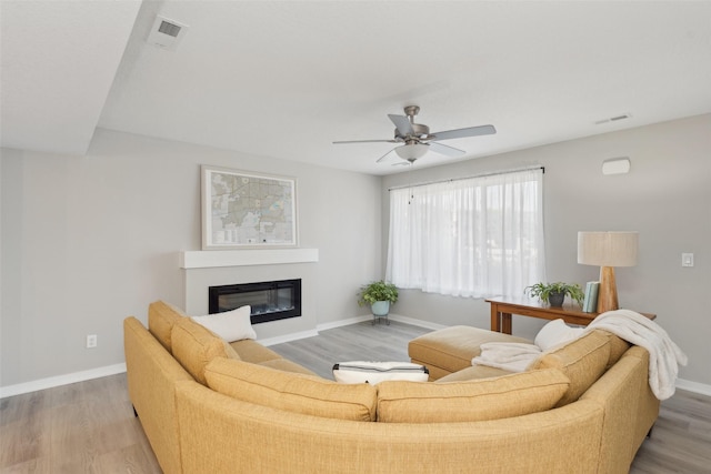 2642 SE Osier Ave, West Des Moines, IA 50265 - living area featuring light wood finished floors, a ceiling fan, and a glass covered fireplace