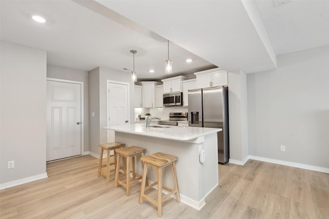 2642 SE Osier Ave, West Des Moines, IA 50265 - kitchen featuring appliances with stainless steel finishes, recessed lighting, light wood finished floors, white cabinetry, and a breakfast bar