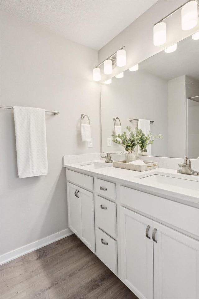 2642 SE Osier Ave, West Des Moines, IA 50265 - bathroom featuring double vanity, wood finished floors, a textured ceiling, and a shower
