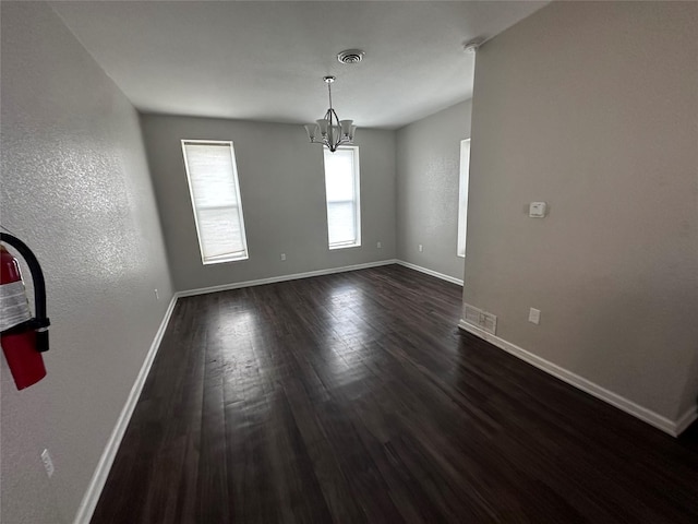 2400 SE 8th St, Des Moines, IA 50315 - spare room featuring baseboards, dark wood-style flooring, and a chandelier