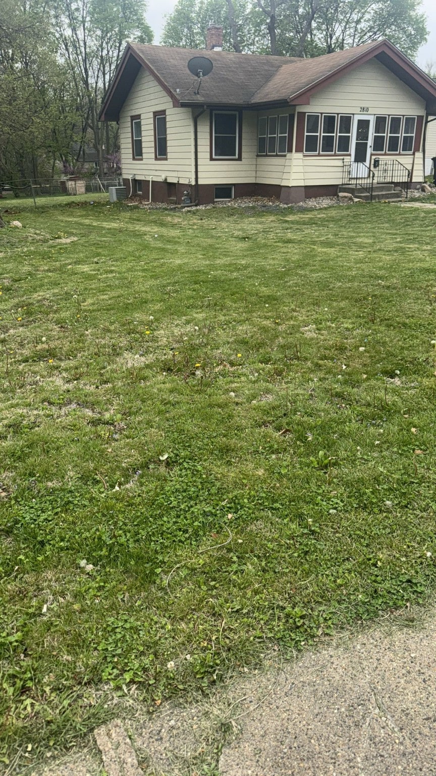 back of property with a chimney and a lawn