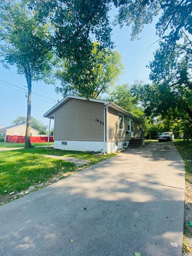 view of home's exterior featuring concrete driveway and a lawn