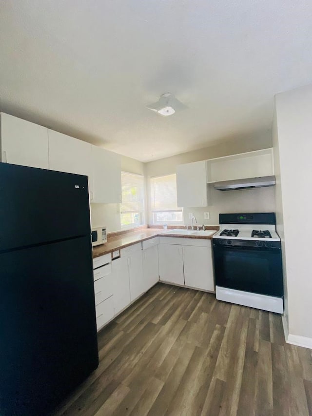 kitchen with freestanding refrigerator, gas stove, dark wood-style flooring, and a sink