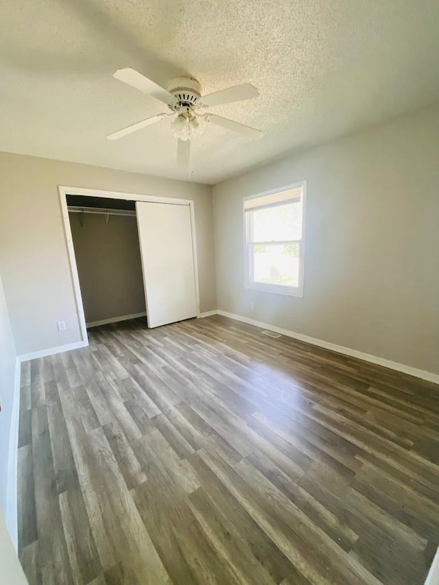 unfurnished bedroom featuring baseboards, wood finished floors, a textured ceiling, a closet, and ceiling fan