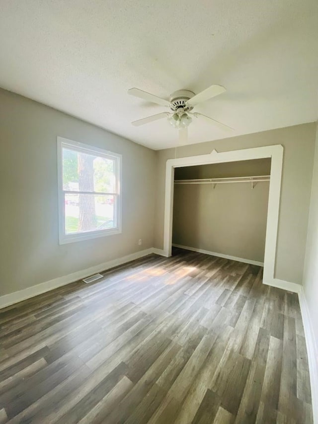 unfurnished bedroom featuring baseboards, wood finished floors, a closet, a ceiling fan, and a textured ceiling