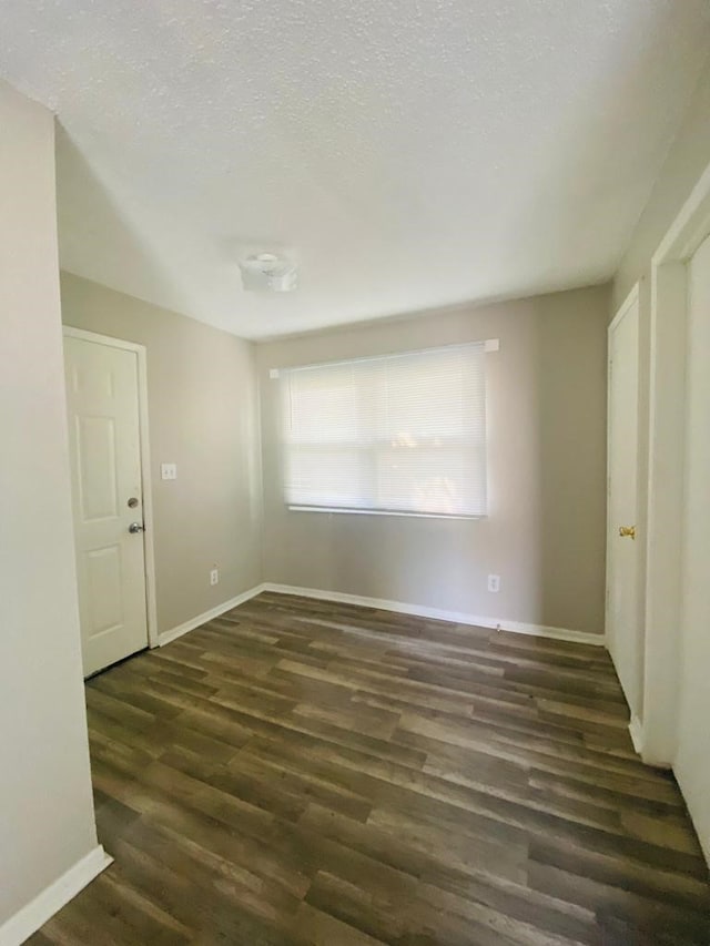 unfurnished bedroom featuring wood finished floors, baseboards, and a textured ceiling