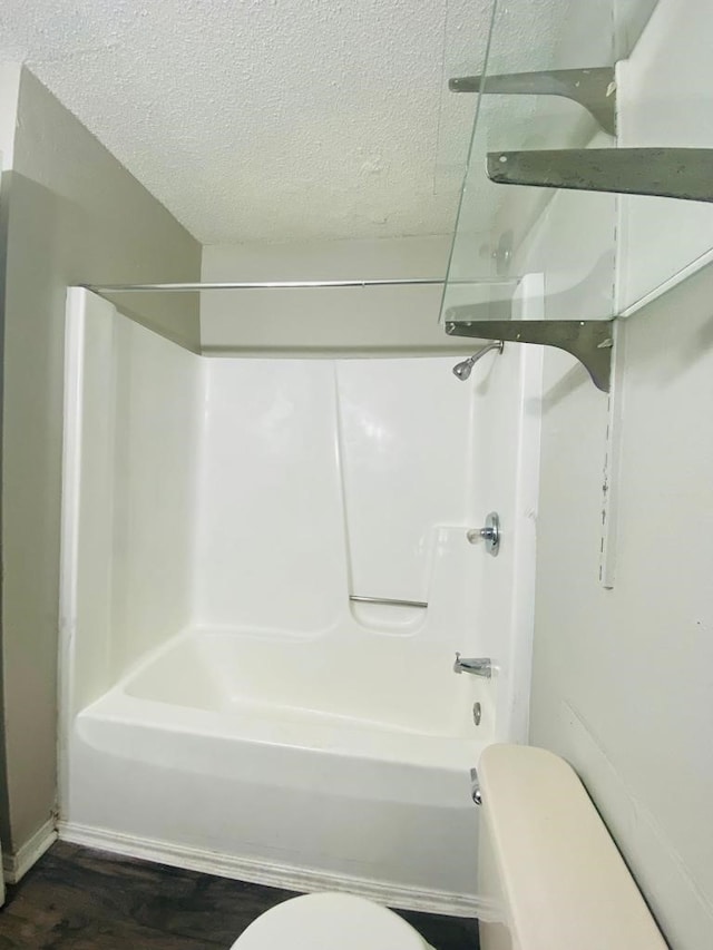 full bath with toilet, wood finished floors, a textured ceiling, and  shower combination