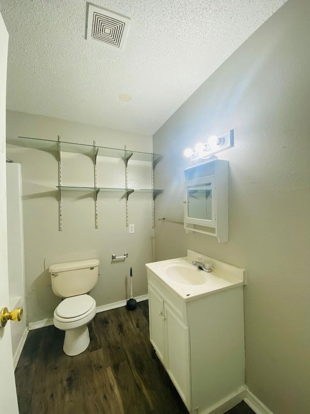 bathroom featuring wood finished floors, a textured ceiling, vanity, toilet, and baseboards
