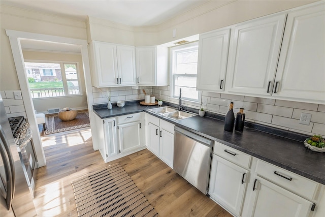1916 Locust St, West Des Moines, IA 50265 - kitchen with appliances with stainless steel finishes, dark countertops, white cabinetry, light wood-style flooring, and decorative backsplash