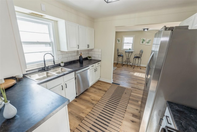 1916 Locust St, West Des Moines, IA 50265 - kitchen with a sink, appliances with stainless steel finishes, white cabinets, dark countertops, and backsplash