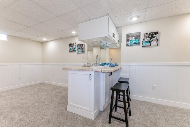 1916 Locust St, West Des Moines, IA 50265 - kitchen with wainscoting, light carpet, a peninsula, a drop ceiling, and white cabinets