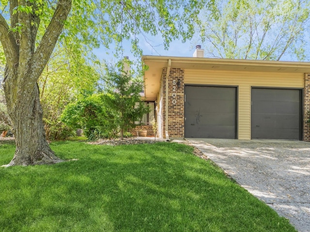 5200 Twana Dr, Des Moines, IA 50310 - view of side of home with a chimney, driveway, an attached garage, a lawn, and brick siding