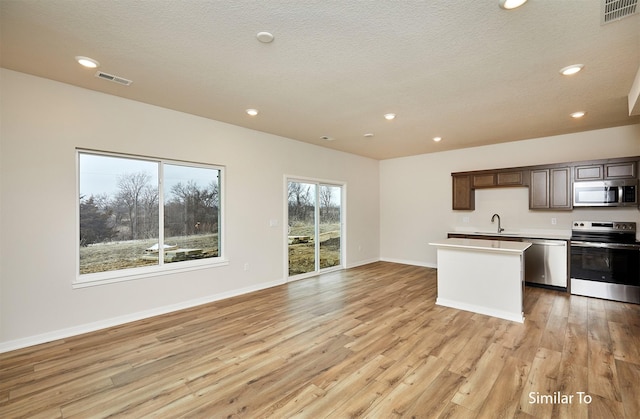 kitchen with stainless steel appliances, a sink, light wood-style floors, recessed lighting, and open floor plan