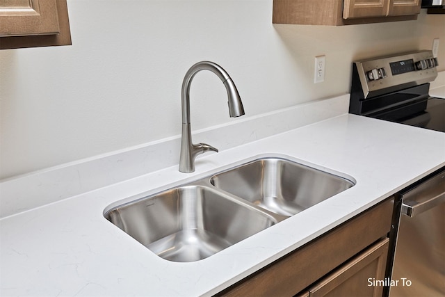 kitchen view of a sink, dishwasher, and light stone countertops