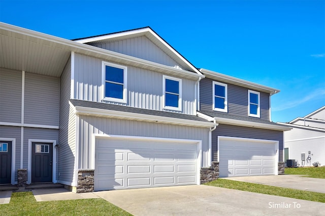 view of property with a garage, stone siding, central AC unit, and driveway