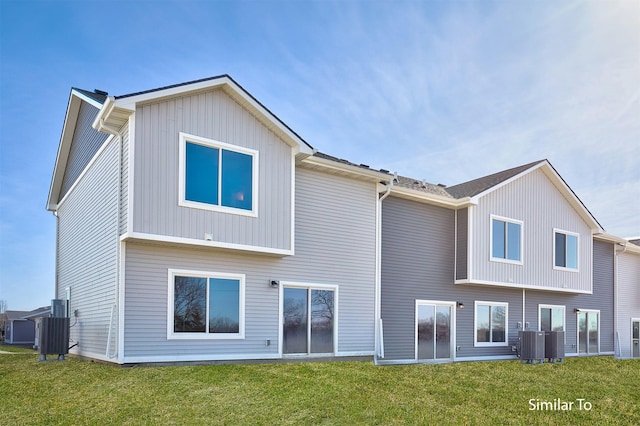 rear view of property featuring a yard and central AC