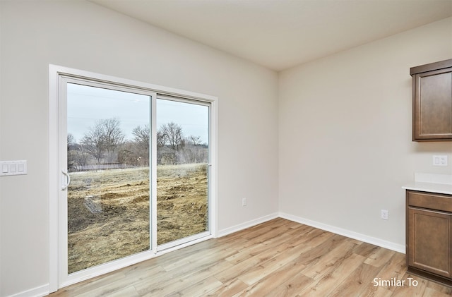unfurnished dining area featuring light wood-type flooring and baseboards