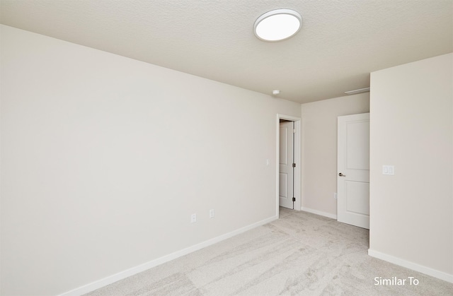 spare room with baseboards and light carpet