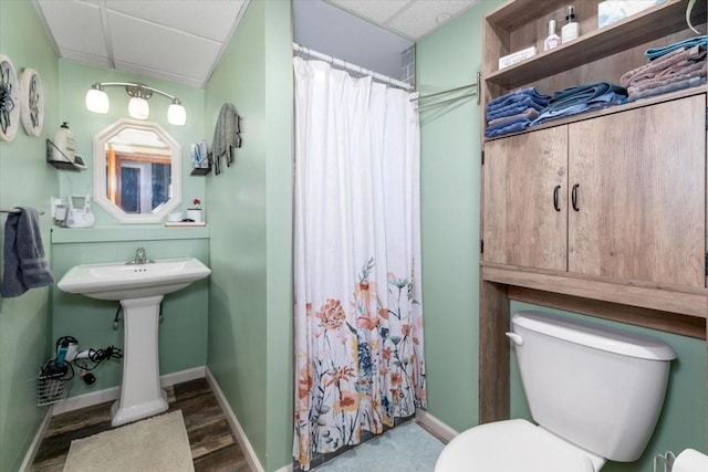 full bath with a drop ceiling, toilet, baseboards, curtained shower, and wood finished floors