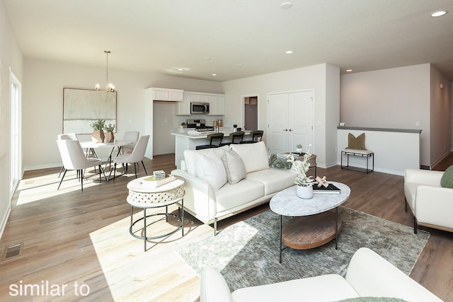 living area featuring light wood-type flooring, recessed lighting, a chandelier, and baseboards
