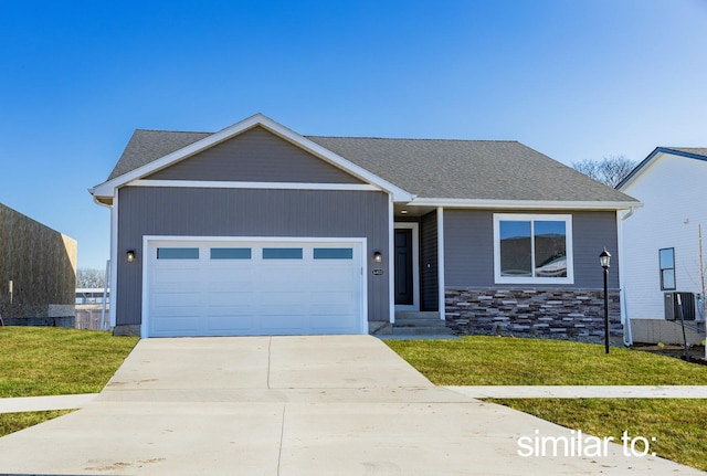 view of front of property featuring a front lawn, an attached garage, driveway, central AC unit, and a shingled roof