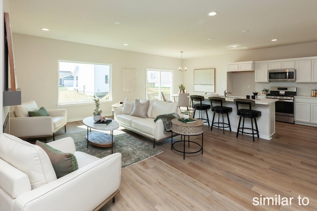 living area with recessed lighting, light wood-style flooring, baseboards, and a chandelier