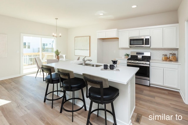 kitchen featuring appliances with stainless steel finishes, a sink, tasteful backsplash, light countertops, and a kitchen breakfast bar