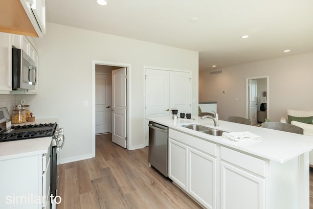 kitchen featuring stainless steel appliances, a sink, light wood-style flooring, white cabinetry, and recessed lighting