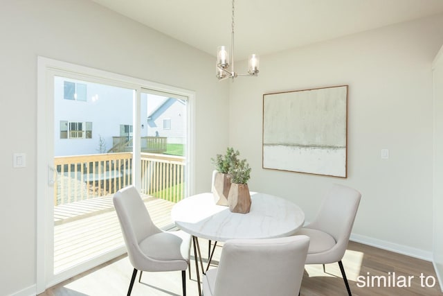 dining area featuring a chandelier, wood finished floors, and baseboards
