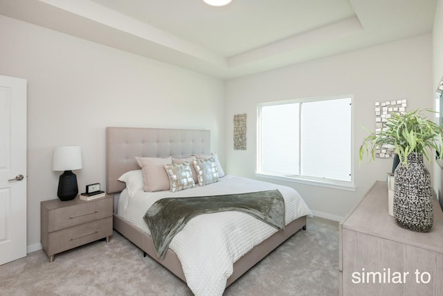 carpeted bedroom featuring baseboards and a tray ceiling