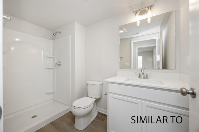 6565 NE 11th Ct, Des Moines, IA 50313 - bathroom featuring wood finished floors, toilet, a shower, vanity, and baseboards